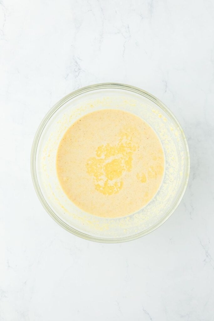 Fully mixed cornbread batter in a glass bowl with melted butter added