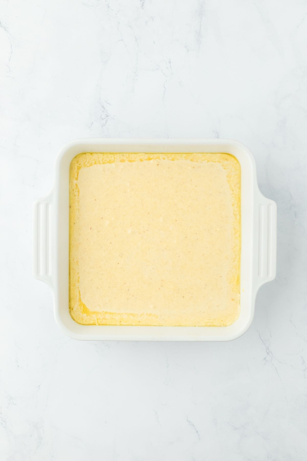 The cornbread batter poured into the baking dish, ready to bake