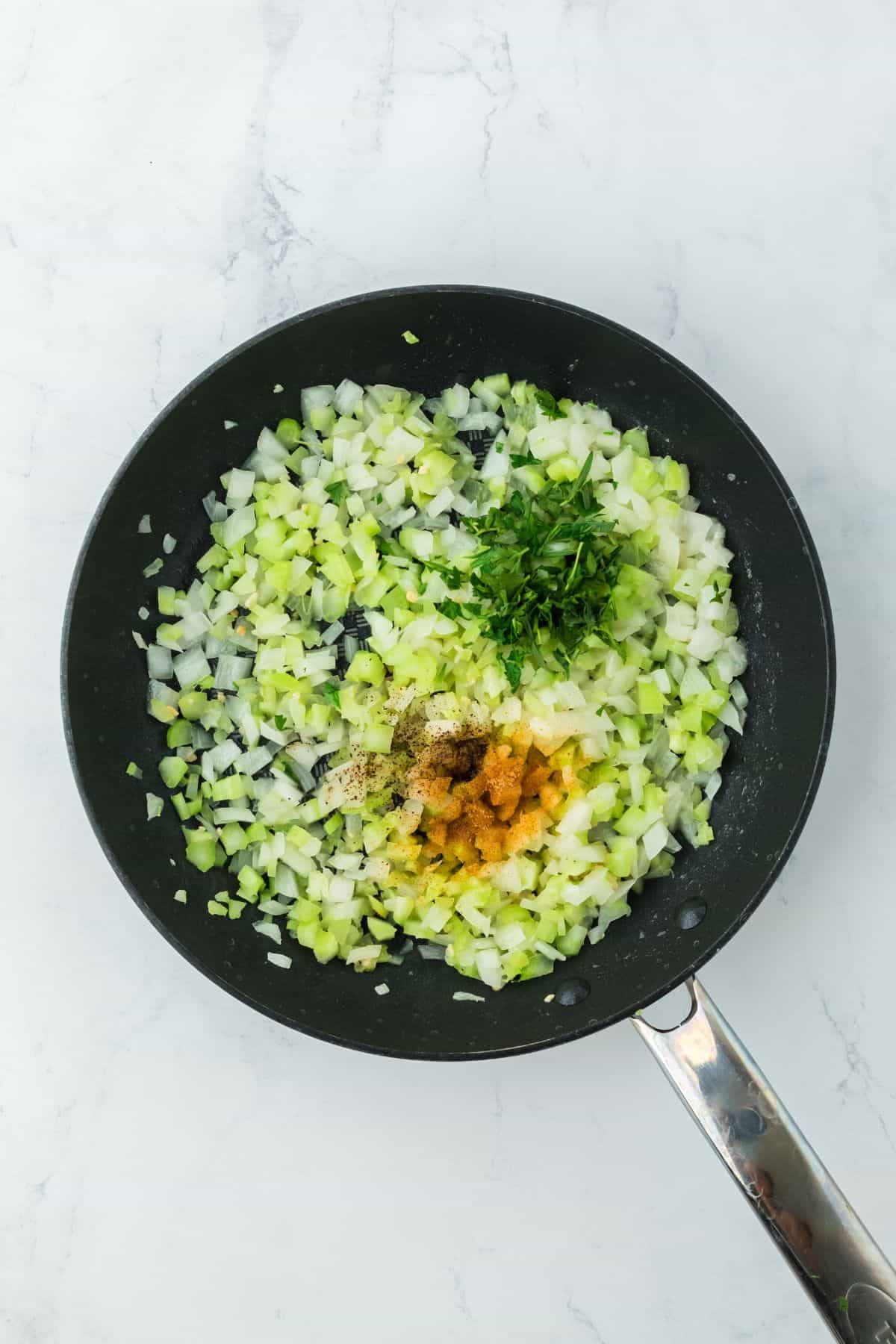 Onions, celery, parsley, and seasonings added to the skillet while cooking