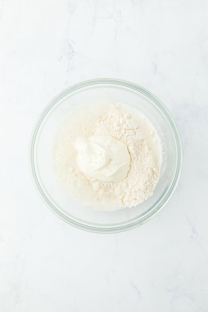 Biscuit flour, sour cream, 7 up in a medium bowl on white countertop