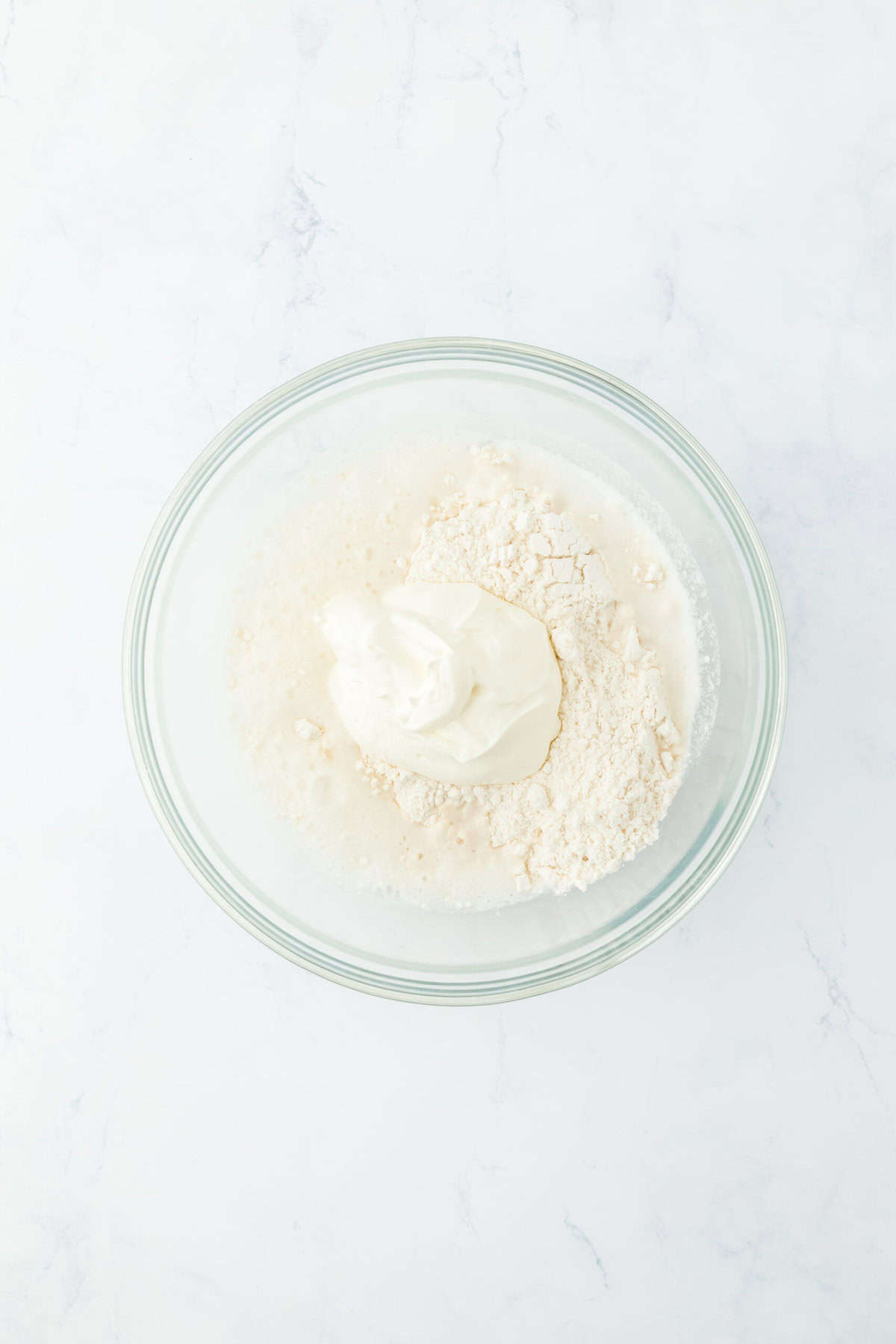 Biscuit flour, sour cream, 7 up in a medium bowl on white countertop