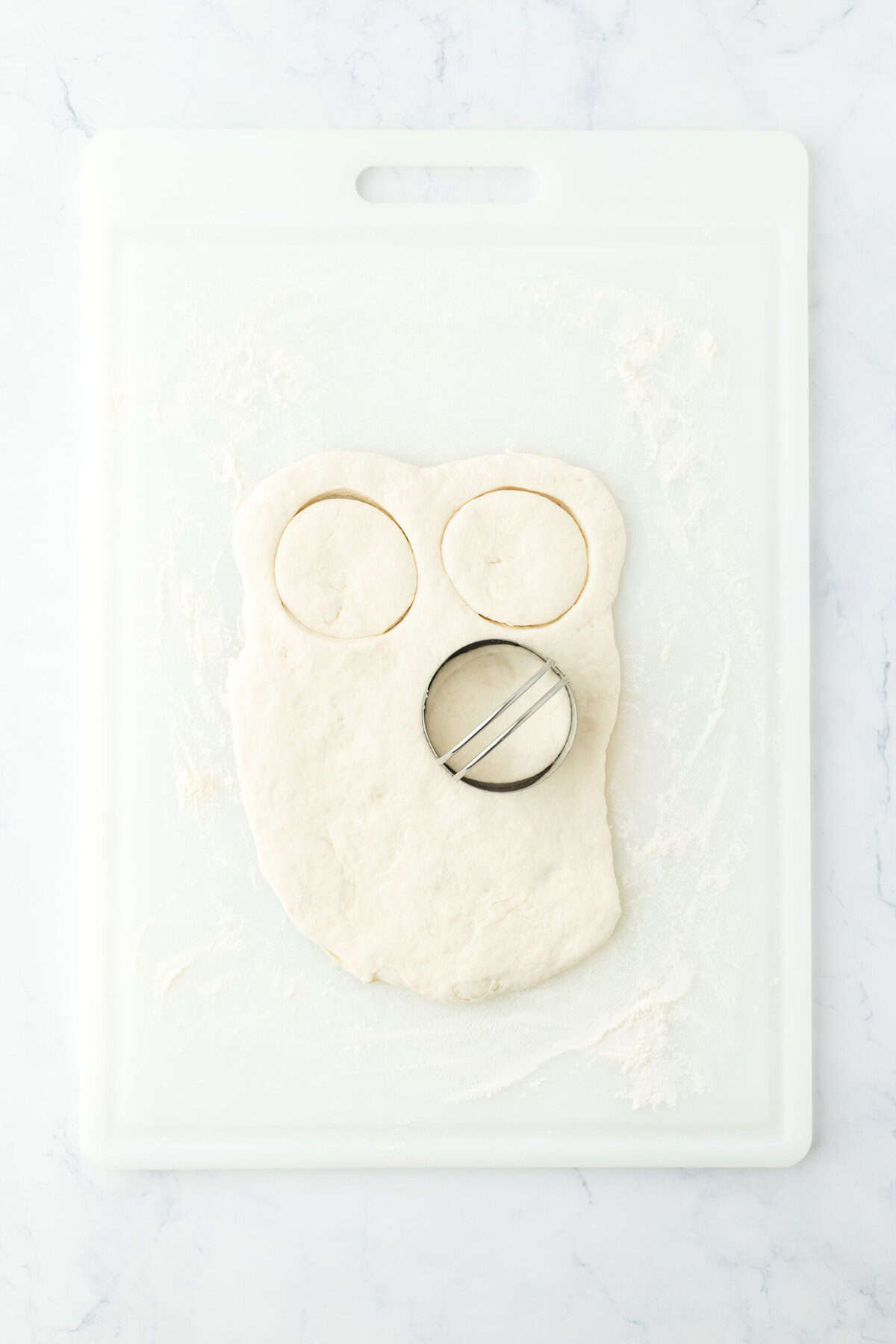 Biscuit dough being cut on a cutting board with round cutters