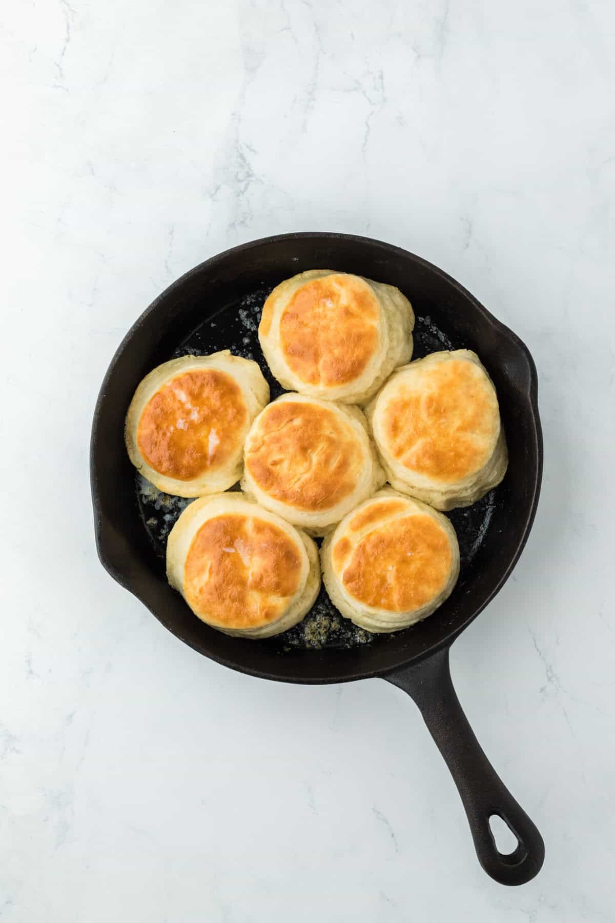 Finished baked biscuits in a cast iron skillet on white countertop