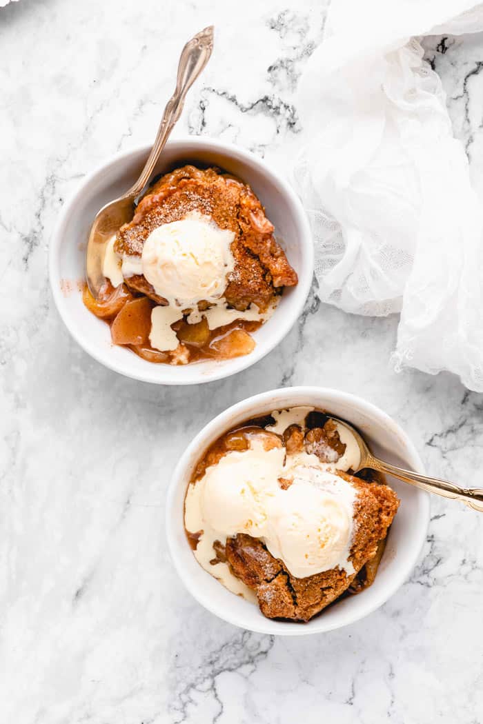 Scoops of cobbler made with spices, apples and ice cream in white bowls