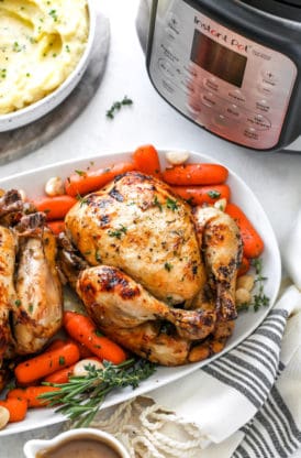 Two cornish hens on a white platter with instant pot in background