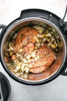Two cornish hens in marinade inside of an instant pot ready to cook