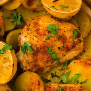 A close up of lemon roast chicken in a dutch oven with lemon halves ready to serve