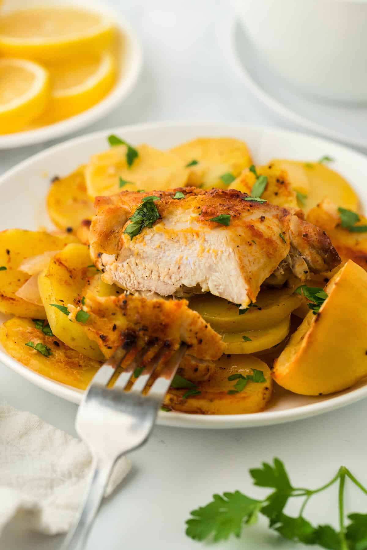 Lemon roast chicken cut into on a white plate with potatoes ready to serve