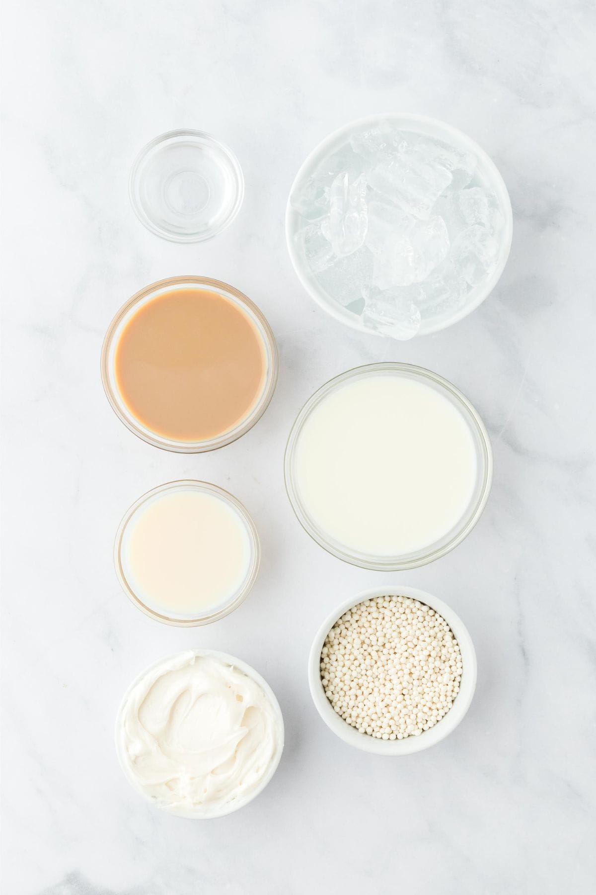 Overhead shot of ingredients for making sugar cookie martini on a marble surface before mixing