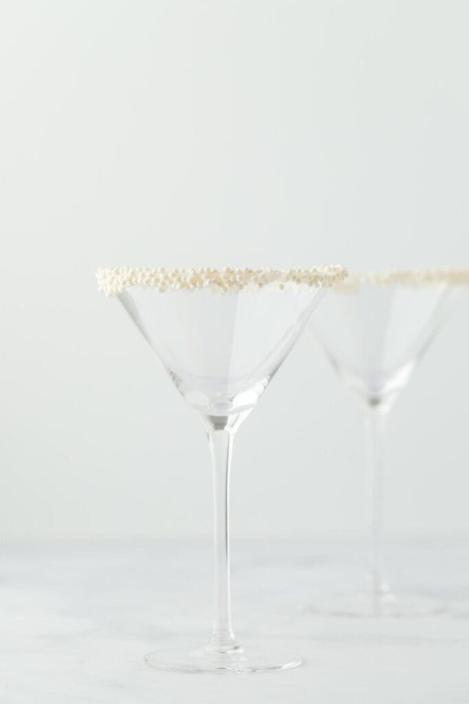 Two martini glasses with sugar pearls around the rims