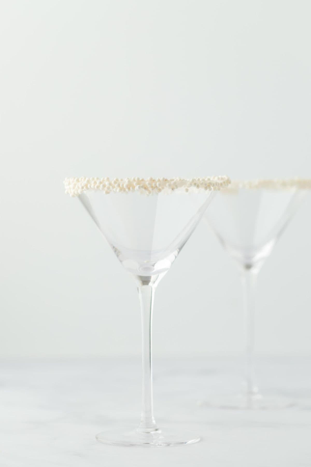 Two martini glasses with sugar pearls around the rims