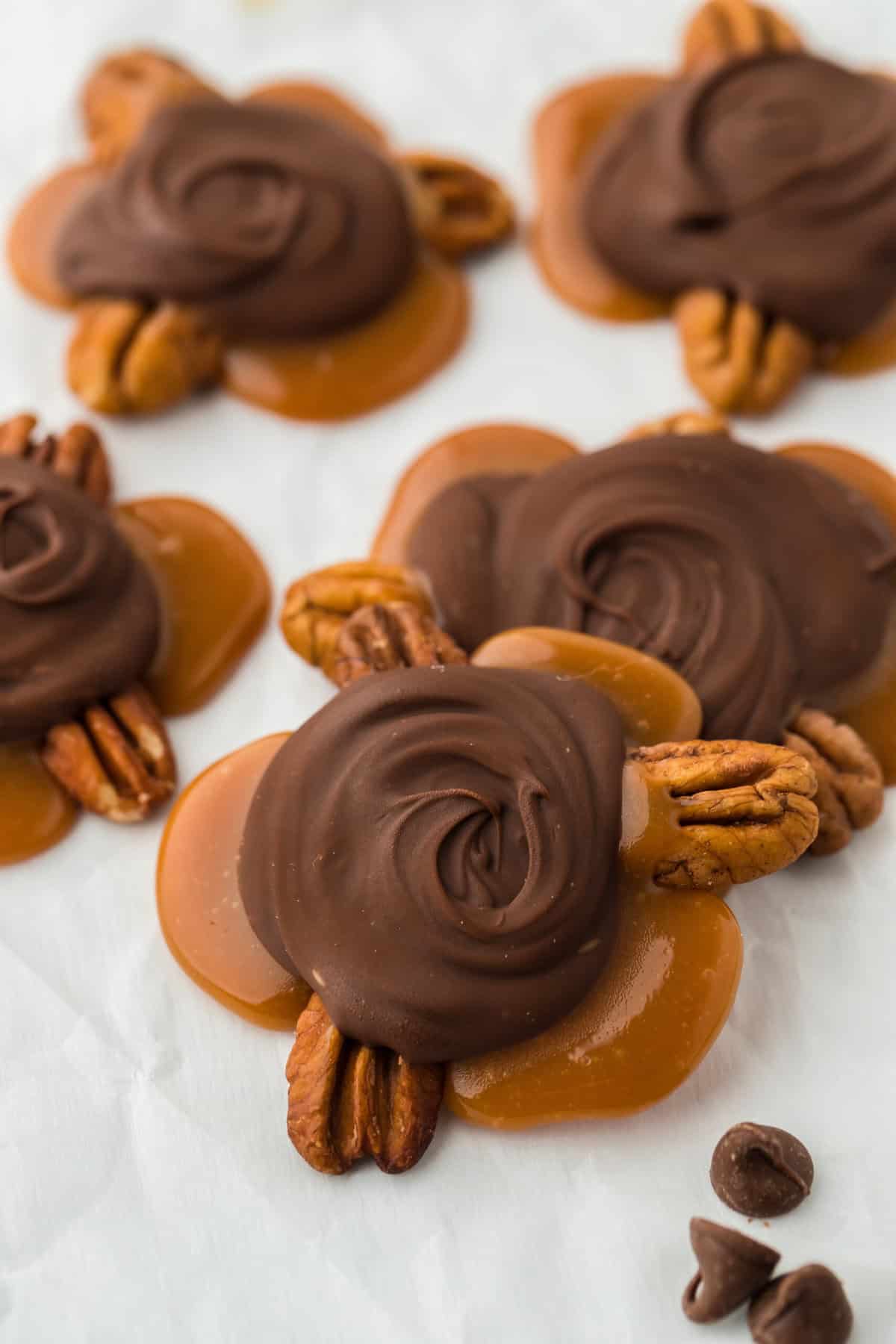 Turtle candy scattered on a white piece of parchment paper ready to enjoy