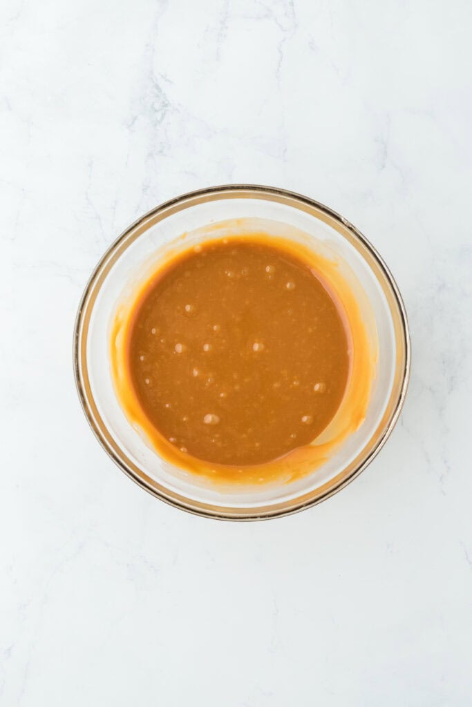 Smooth caramel in a glass bowl on white countetop