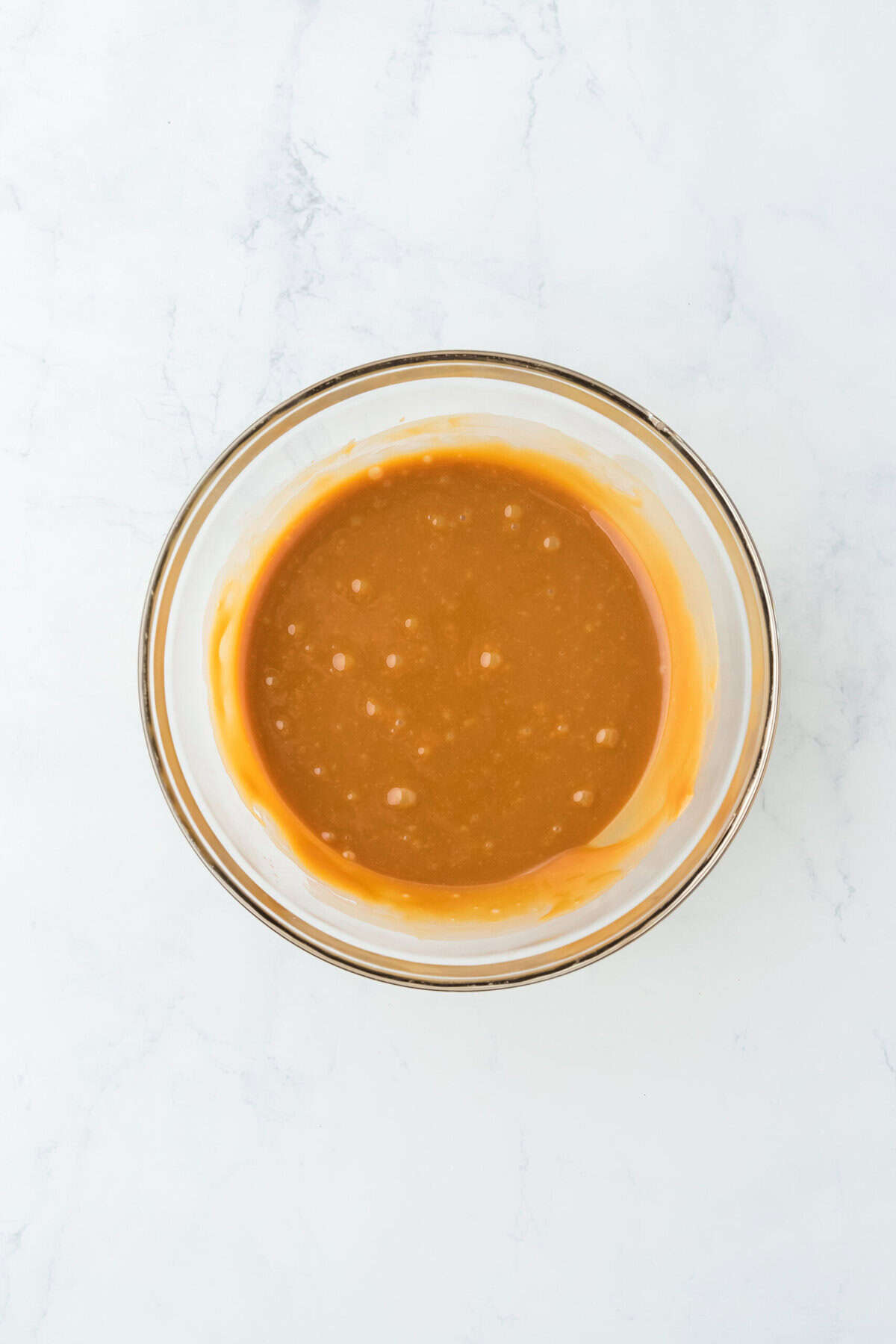 Smooth caramel in a glass bowl on white countetop