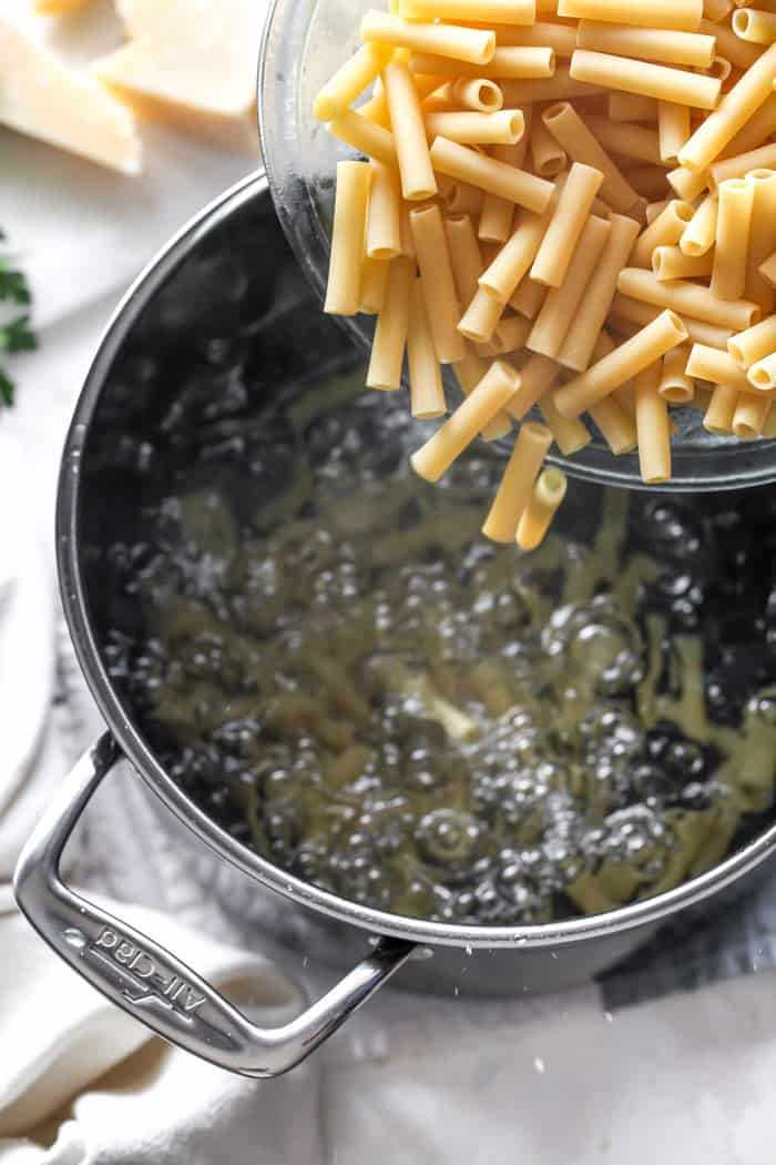 Ziti pasta being poured into boiling water