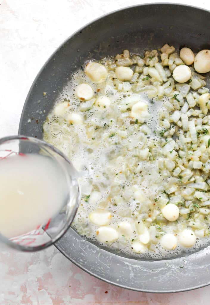Wine being added to garlic in skillet