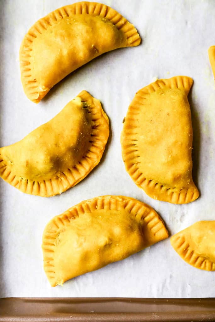 Filling in a curry spiced pastry dough on parchment paper on a baking sheet ready to bake
