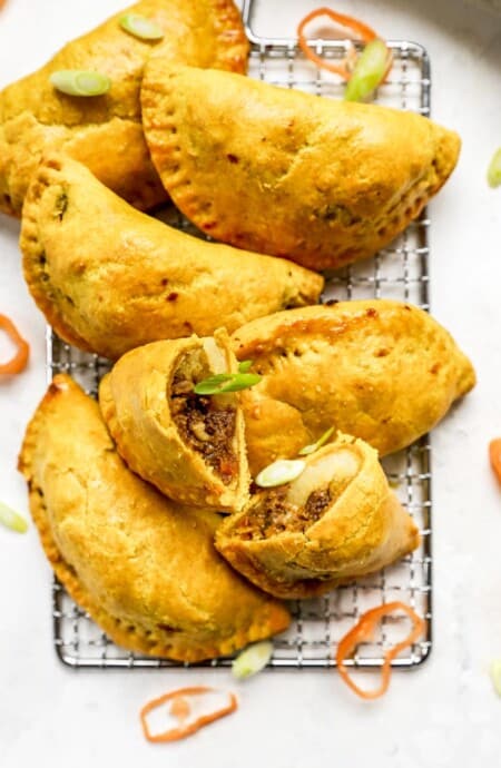 Jamaican beef patties on a wire rack with one cut open ready to enjoy