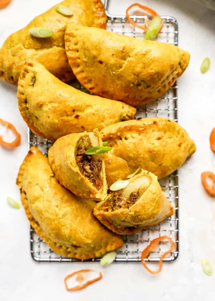 Jamaican beef patties on a wire rack with one cut open ready to enjoy