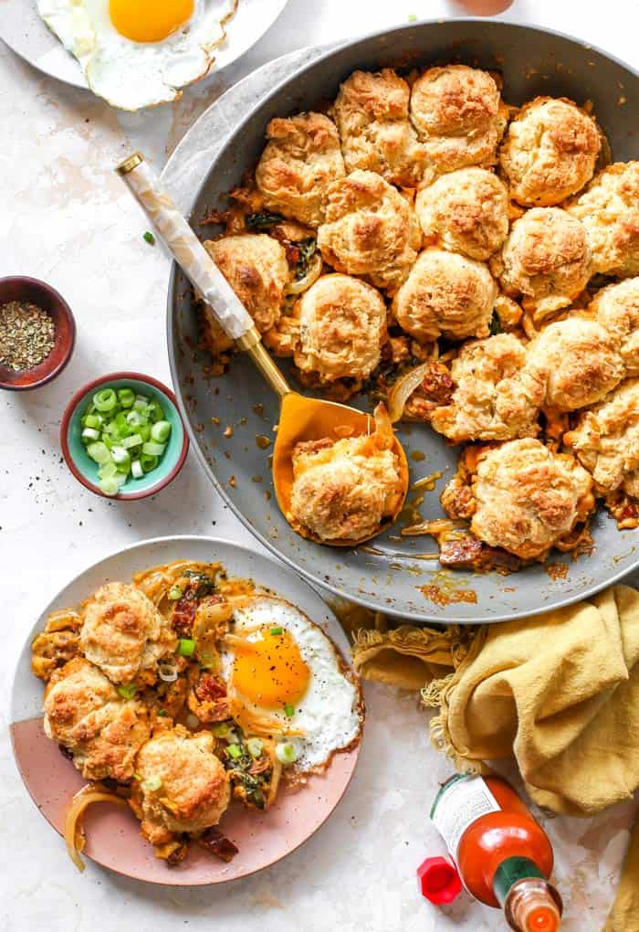 A full breakfast skillet being spooned on a plate ready to enjoy