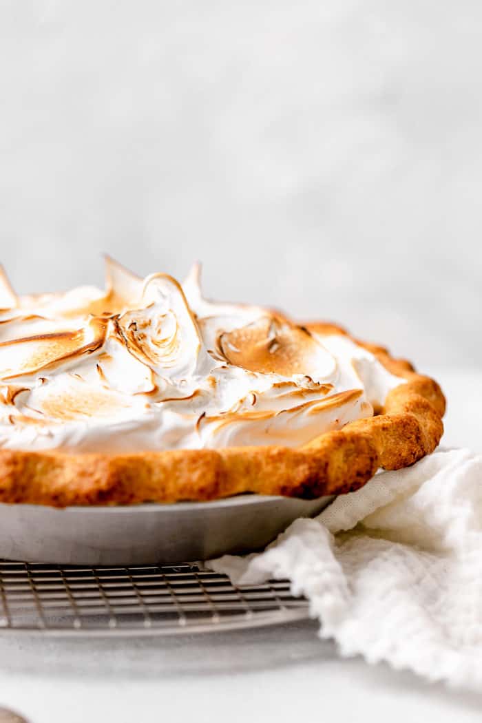 A close up of a lemon meringue pie in a gray plate on a wire rack