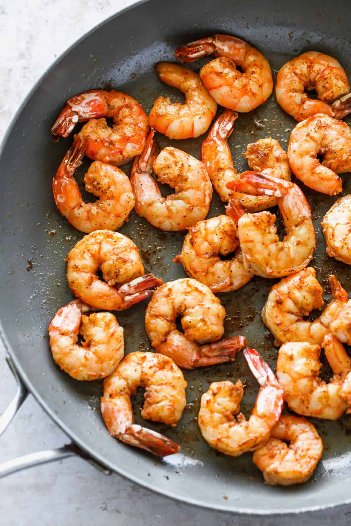 Seasoned shrimp sizzling in a skillet, slightly browned and cooked through