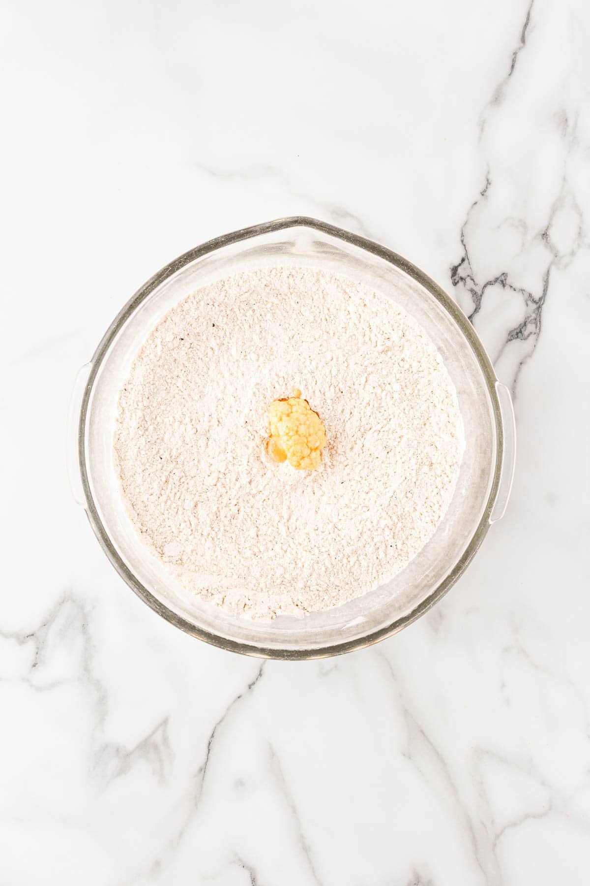 Single cauliflower floret sitting in seasoned flour mixture