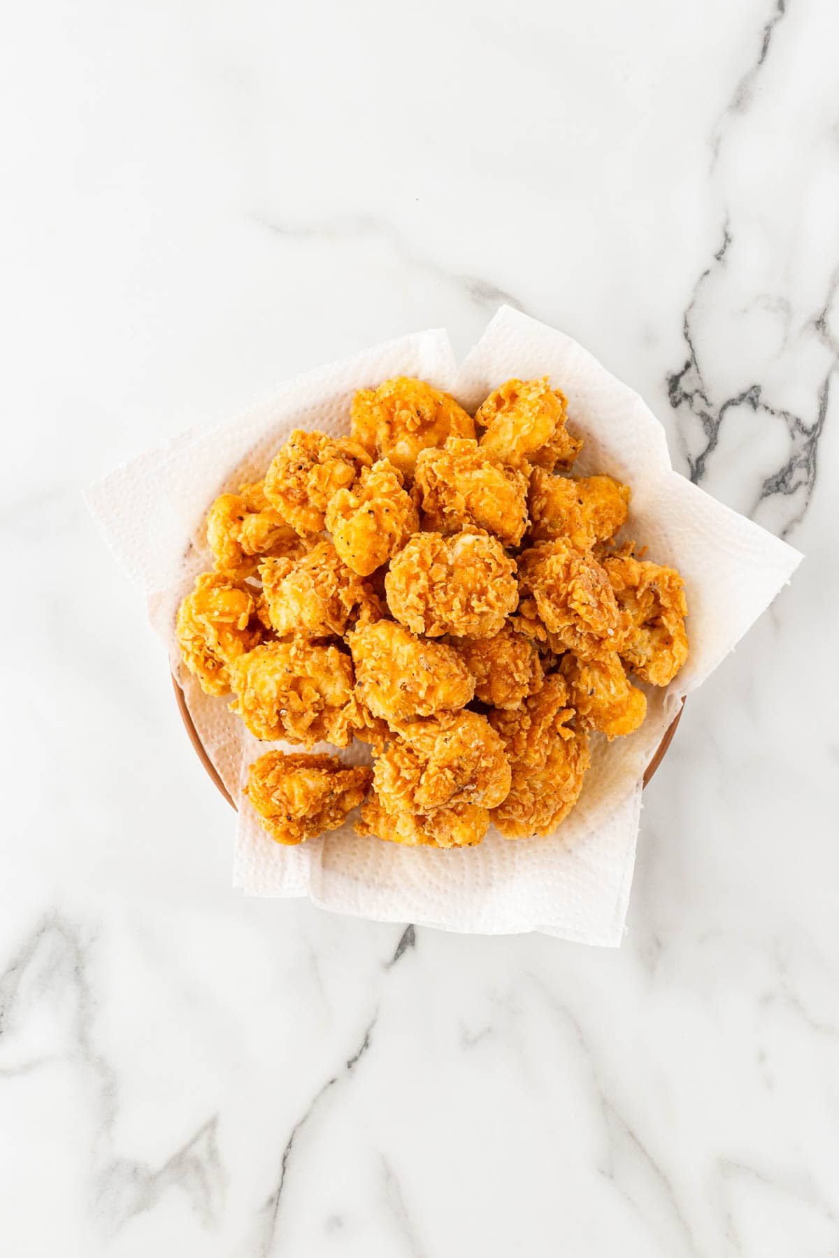 Plate lined with paper towels topped with freshly fried cauliflower bites