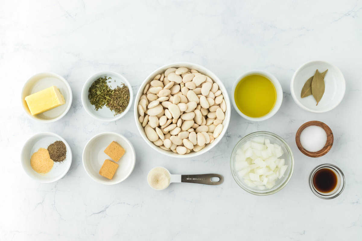 lima beans, spices, butter, oil, herbs and onions in small bowls on a white background