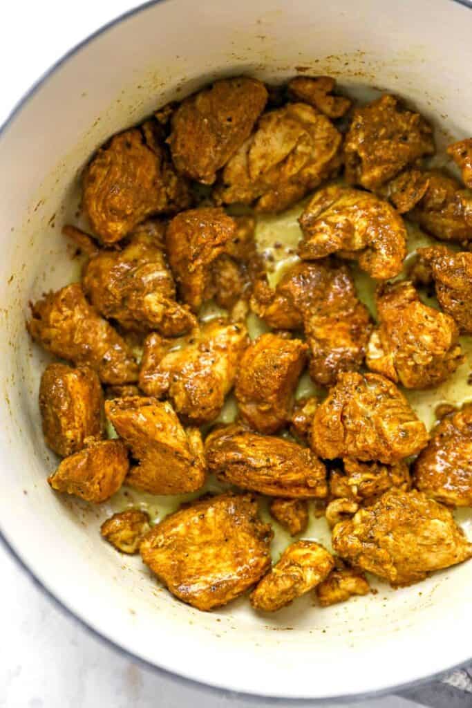 A delicious curry spiced chicken being sauteed in a large pot