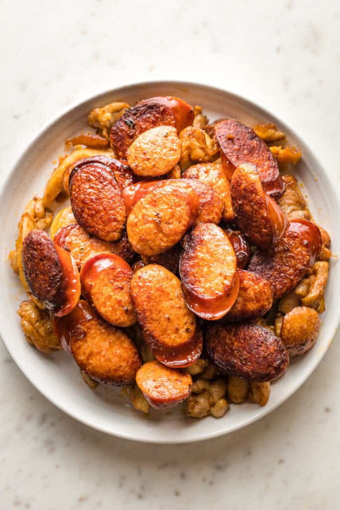 Andouille sausage on a white plate with chicken