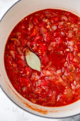 Fresh crushed tomatoes in a large pot with a bay leave simmering
