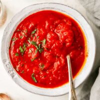 Delicious smooth marinara sauce in a white bowl with a spoon ready to serve