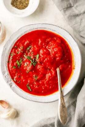 Delicious smooth marinara sauce in a white bowl with a spoon ready to serve