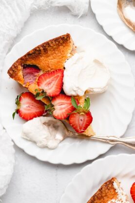 A slice of cornmeal cake on a plate with berries and whipped cream