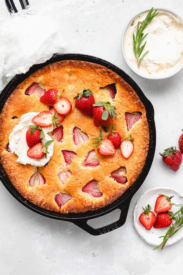 A delicious strawberry skillet cake with whipped cream and fresh berries on top