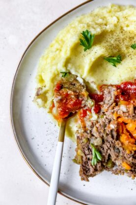 A slice of stuffed meatloaf on mashed potatoes with a fork eating it