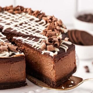 chocolate cheesecake slice being pulled from a whole cheesecake on a serving spoon