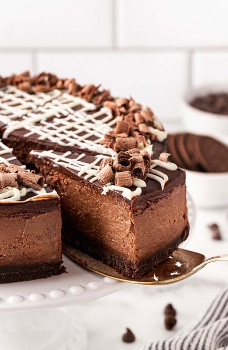 chocolate cheesecake slice being pulled from a whole cheesecake on a serving spoon