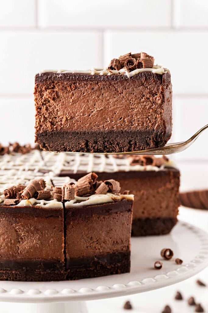 Side view of a slice of chocolate cheesecake showing the crust, filling and topping