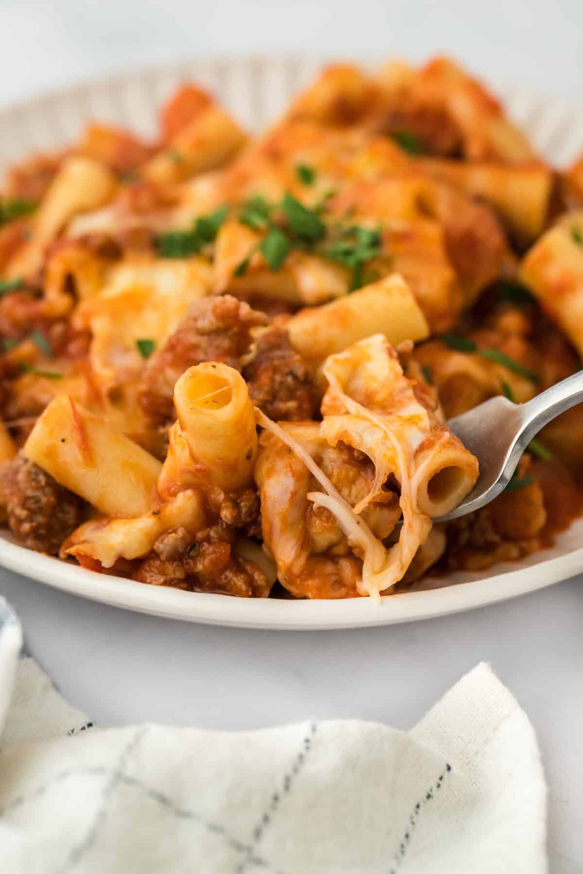 A spoon scooping ziti on white background