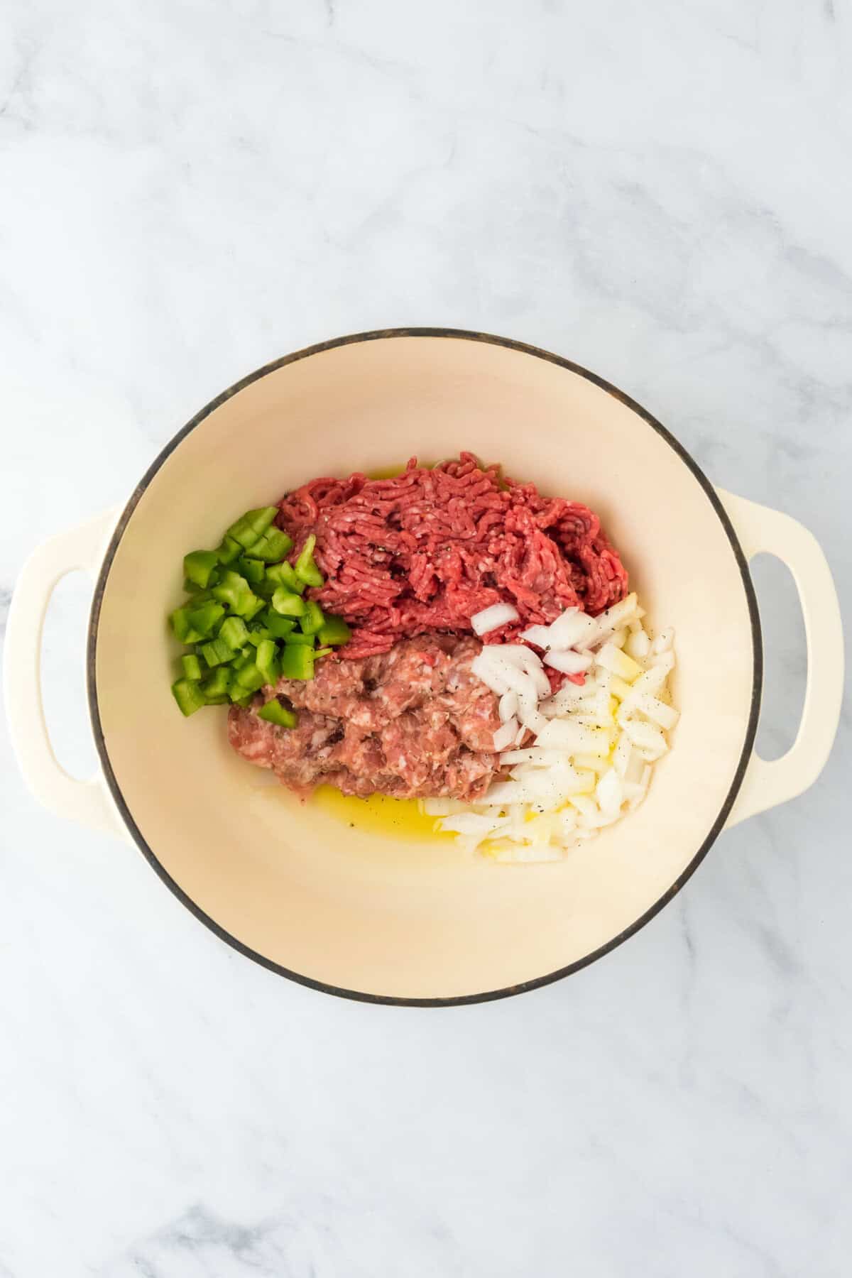 Sausage, ground turkey, onion, green pepper, onion and salt and pepper in a pot with olive oil on white background