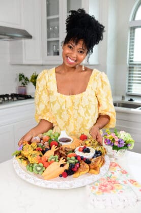 Jocelyn Delk Adams holding a breakfast board filled with goodies ready to enjoy