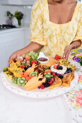 A close up of a brunch board to serve on a holiday with brown hands holding it up