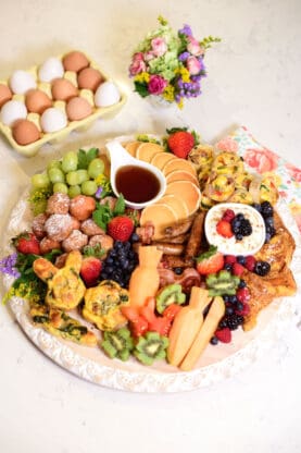 A close up of a breakfast board filled with pancakes, fruit, french toast and other incredible items ready to enjoy