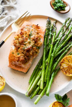 A stuffed salmon filet with crab on a plate with asparagus