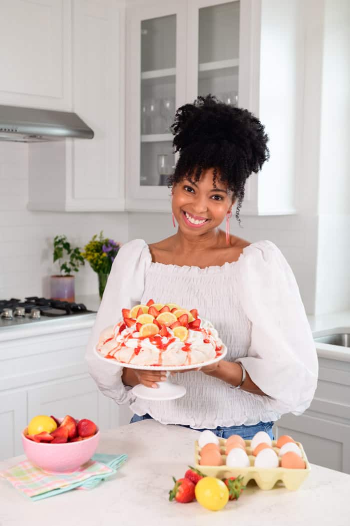 Jocelyn Delk Adams holding a spring pavlova in a white kitchen ready to enjoy
