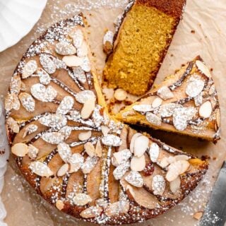 An overhead of a round almond cake with two slices cut out ready to serve