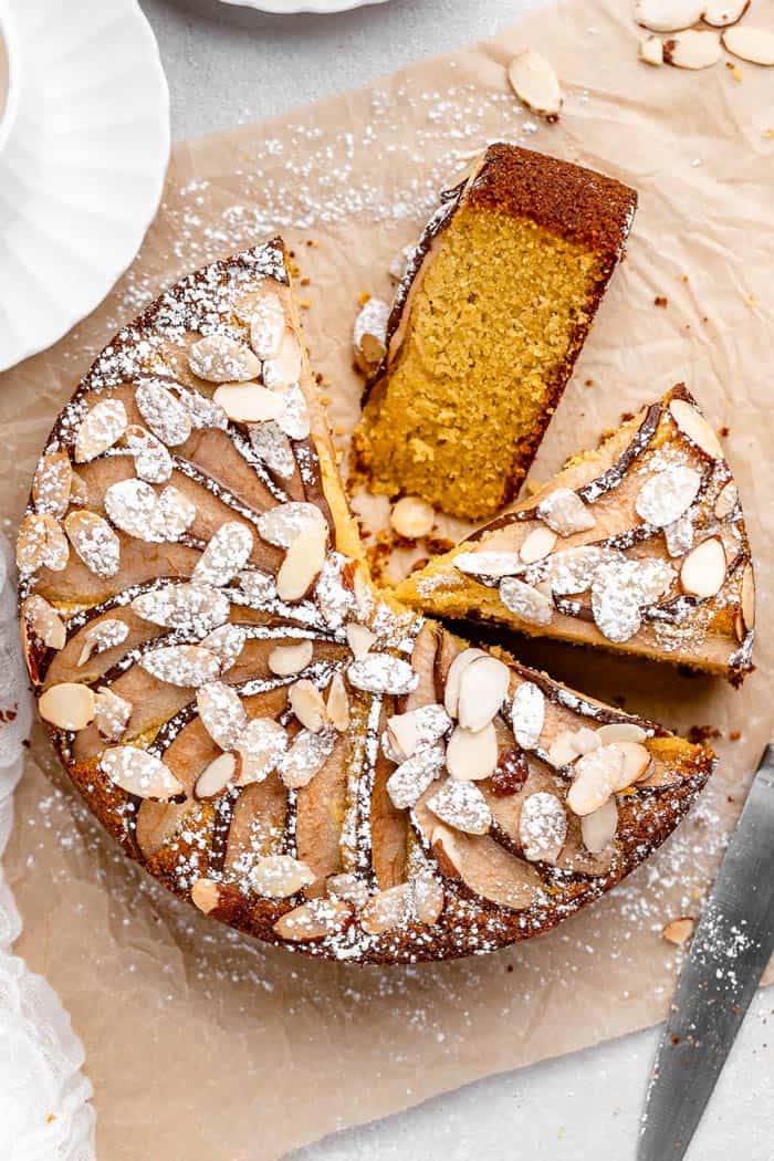 An overhead of a round almond cake with two slices cut out ready to serve