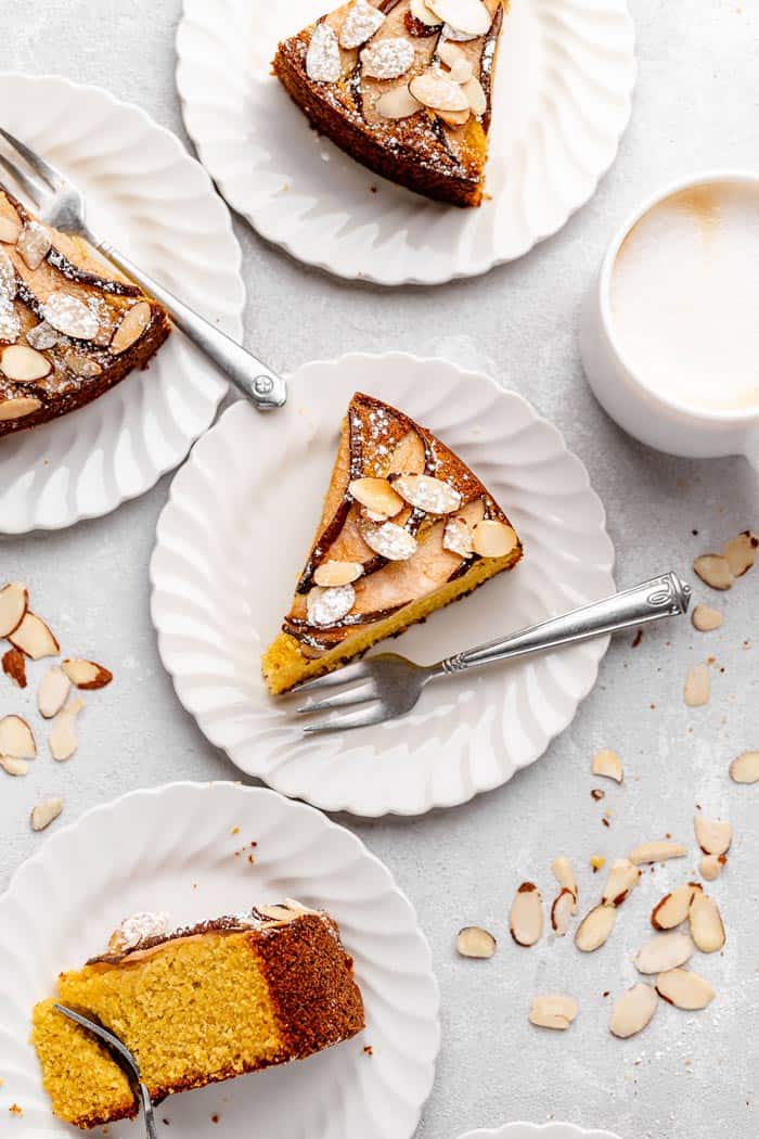 Slices of polenta cake on white plates with silver forks